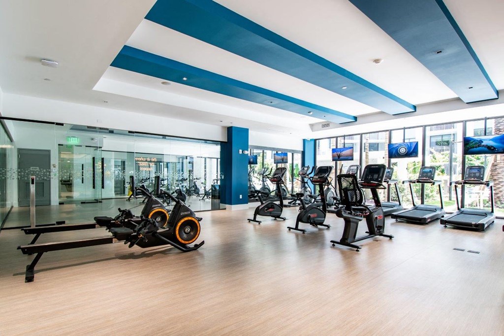a gym with cardio equipment and windows in a building