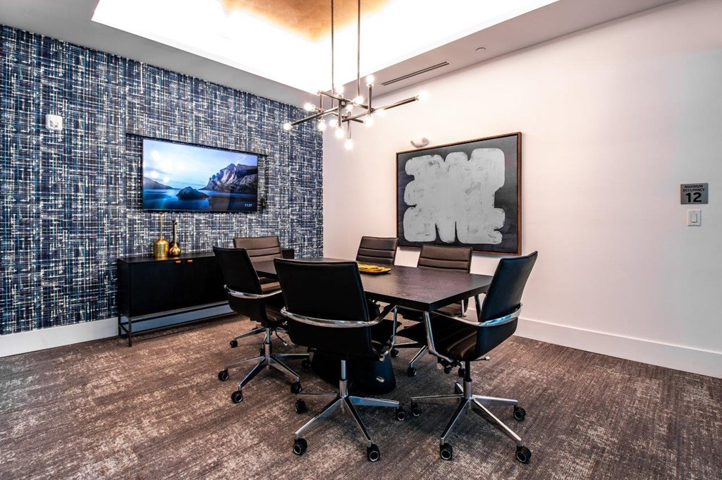 a conference room with a table and chairs and a tv on the wall