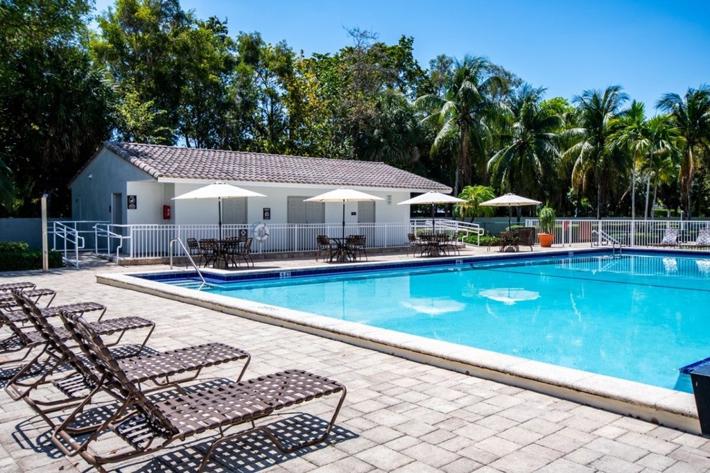 A pool with chairs and a building in the background.