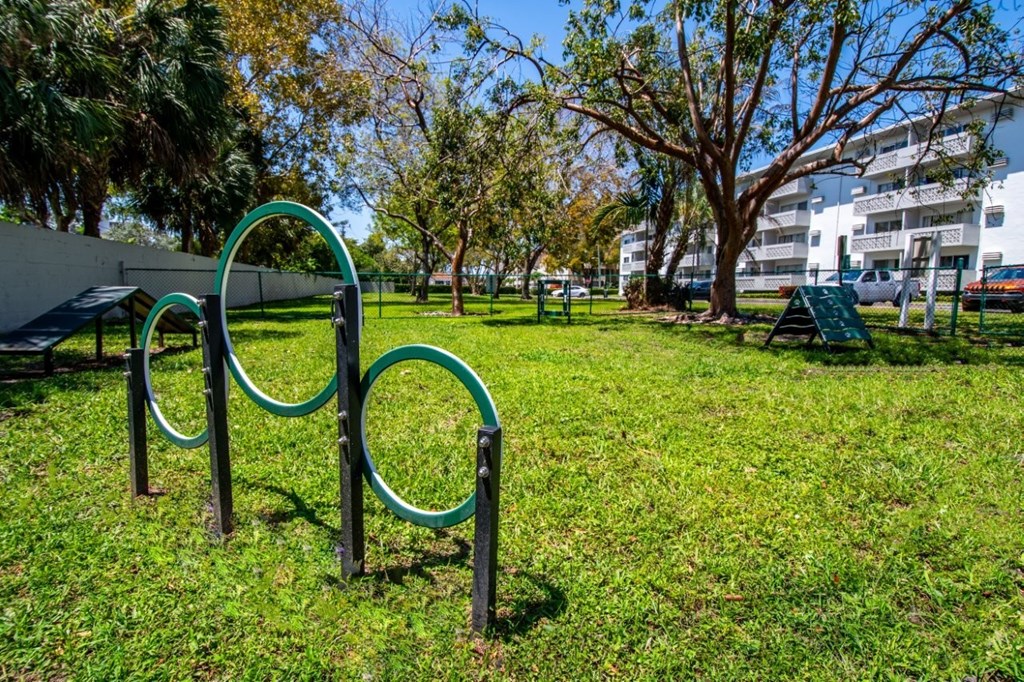 A playground with a green swing set in a grassy area.
