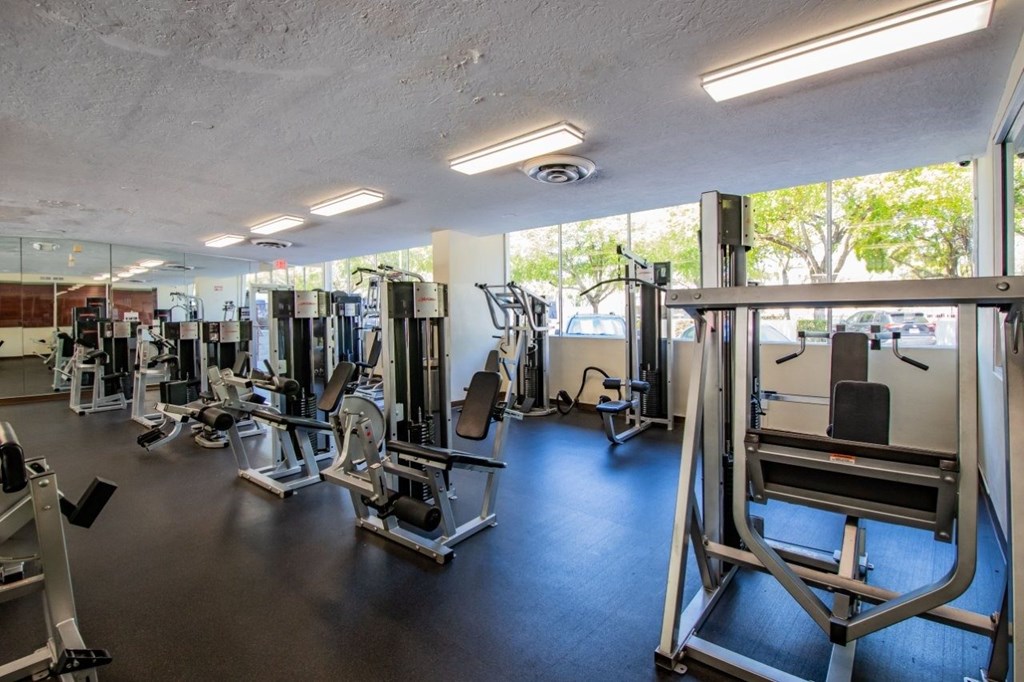 A gym with a variety of equipment including treadmills, weights, and exercise machines.