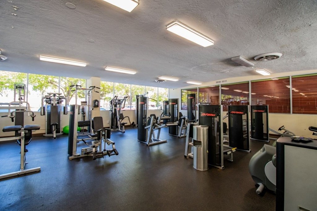 A gym with a variety of equipment including weights and cardio machines.