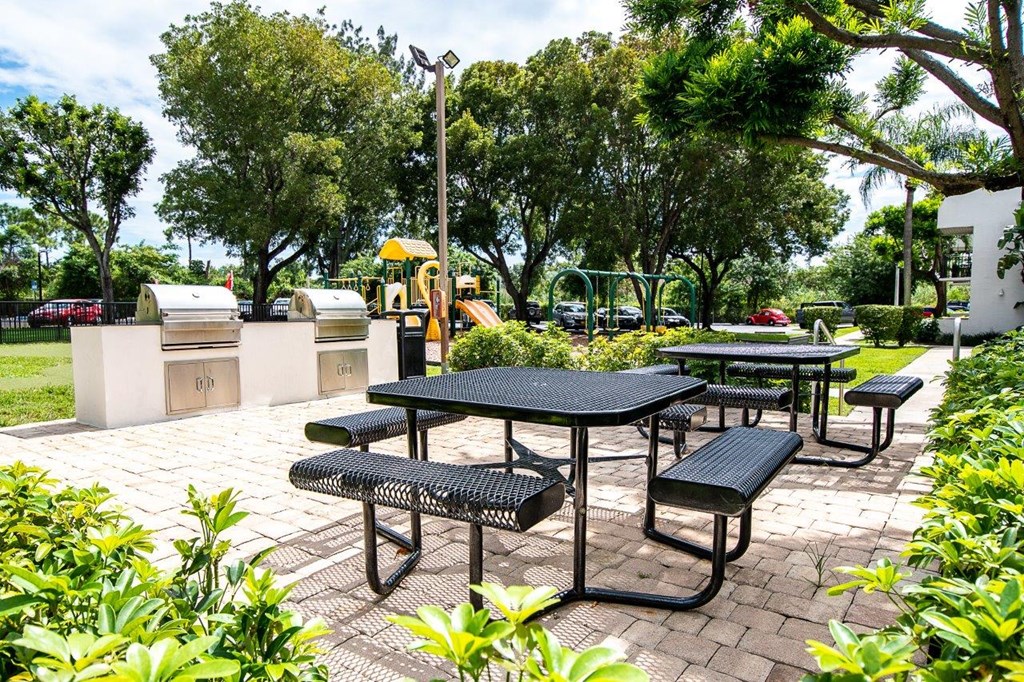 a picnic area with picnic tables and a playground in a park