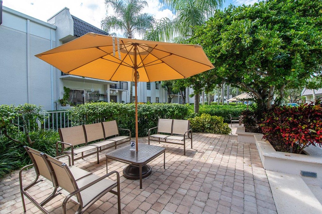 a patio with a table and chairs under an orange umbrella