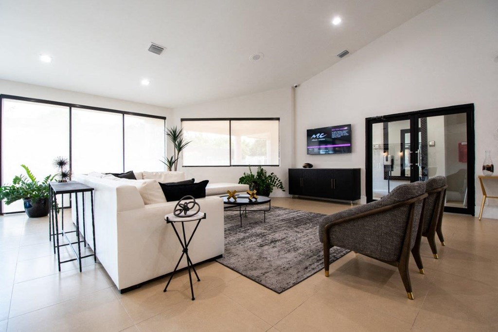 the living room has a white couch and chairs and a television