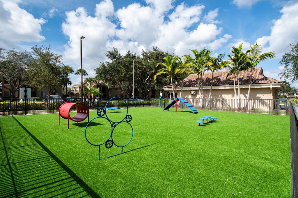 a yard with a playground and a house with palm trees