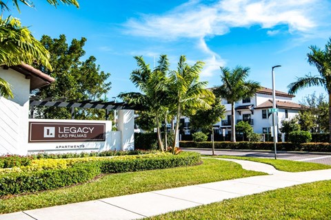 a sidewalk in front of a building with palm trees