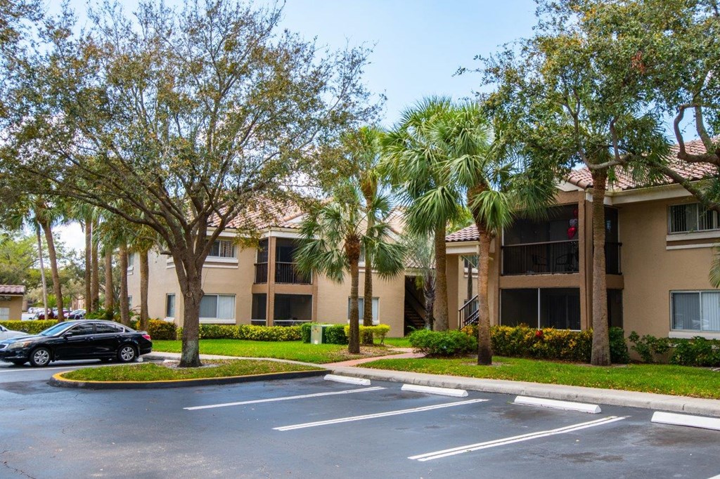 a parking lot in front of an apartment building with palm trees