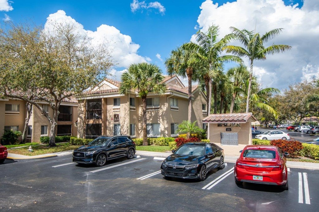 a parking lot in front of an apartment building with cars parked in front
