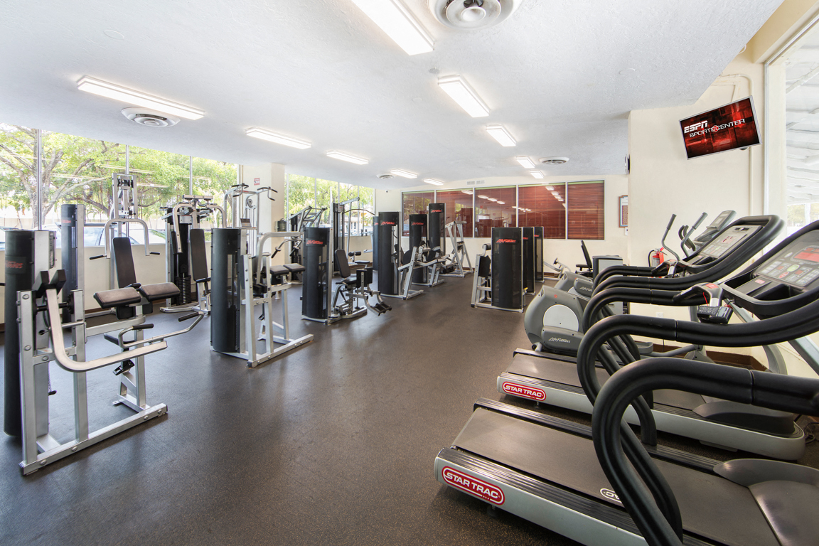 a gym with cardio equipment and weights on the floor