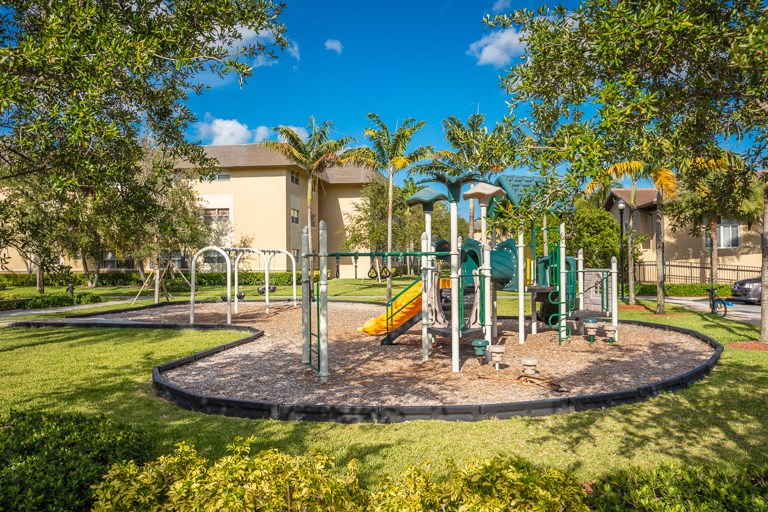 a playground in a park with trees and a building