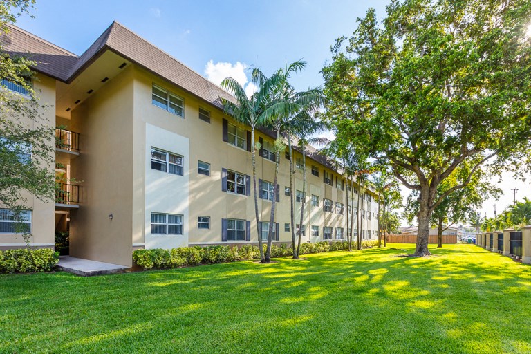 a large building with green grass and trees in front of it