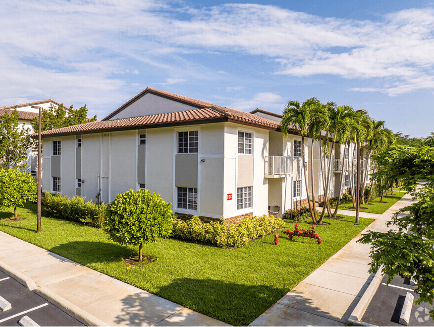 a white house with a yard and palm trees