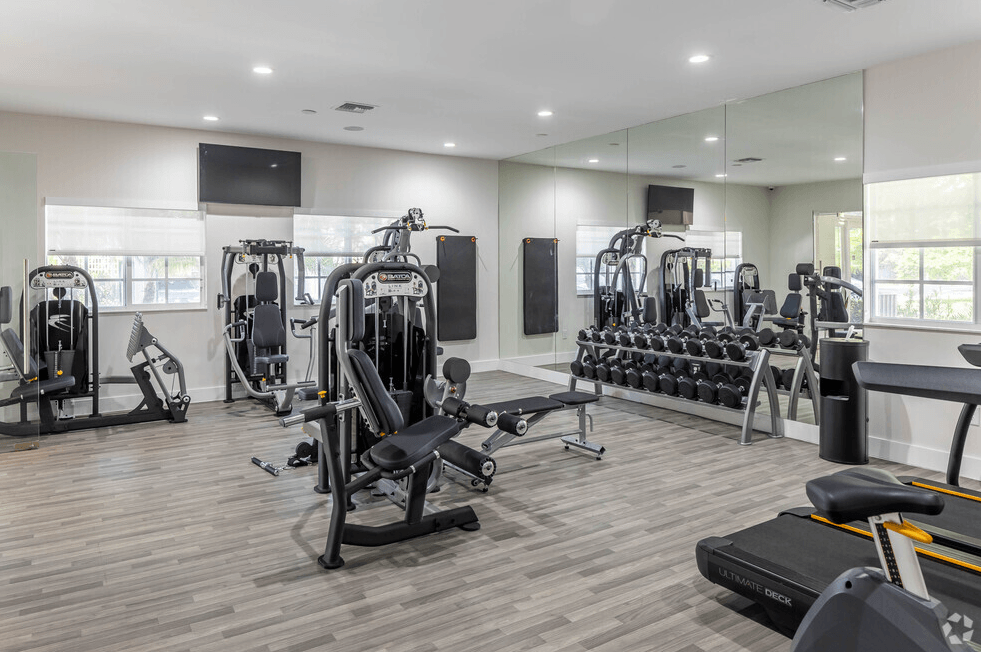 a gym with weights and cardio equipment in a building with windows