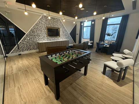 A foosball table is in the middle of a room with a couch and chairs.