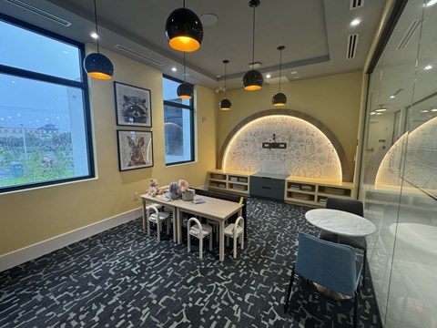 A conference room with a large table and chairs, a TV screen, and framed pictures on the wall.