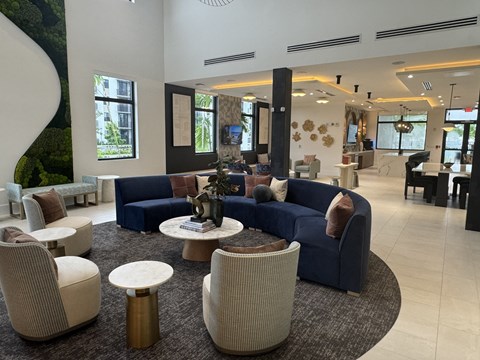 A large, modern living room with a blue sofa and a circular coffee table.