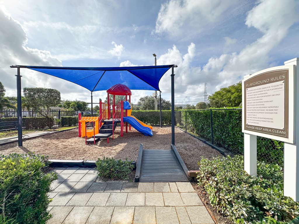 a playground with a swing set and a blue canopy