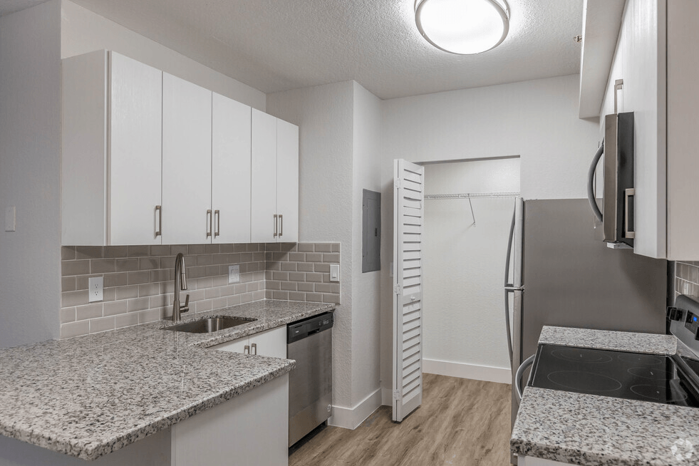 a kitchen with granite counter tops and a stainless steel refrigerator