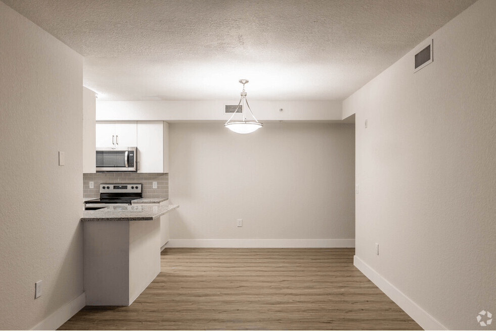 an empty kitchen with wood flooring and white walls