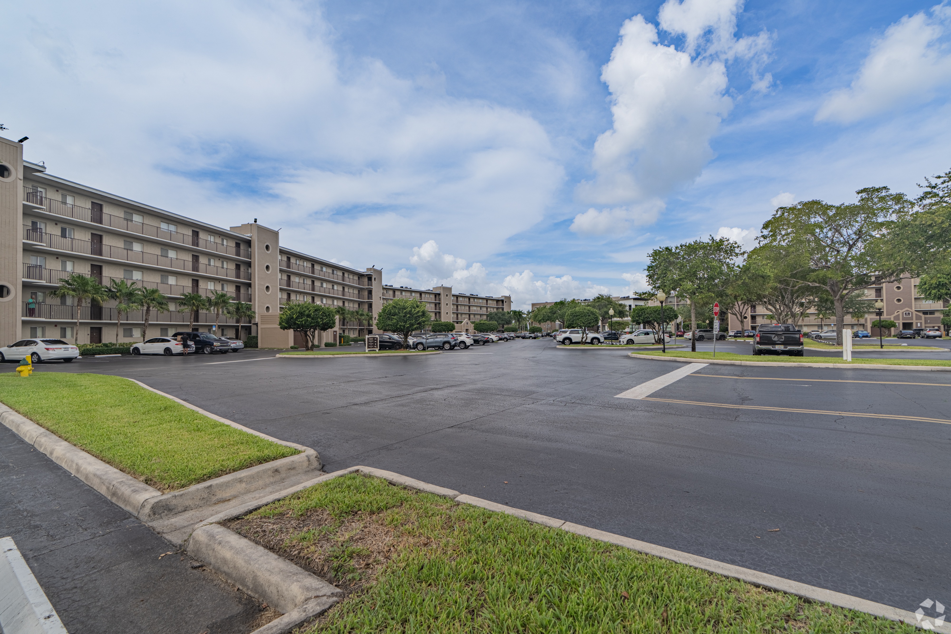 A parking lot in front of a building with a cloudy sky.