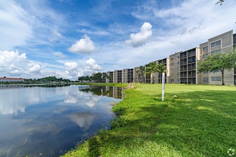 A row of modern buildings are reflected in the water.