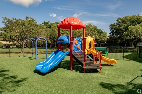 A playground with a blue slide and a red canopy.