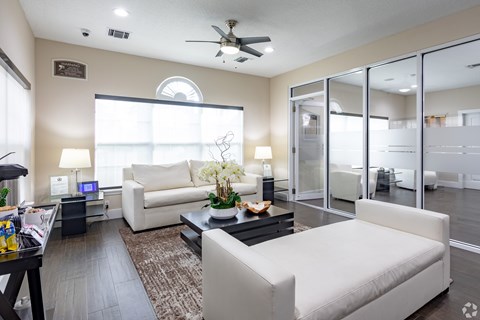 A living room with a white couch and a coffee table with a vase of flowers on it.