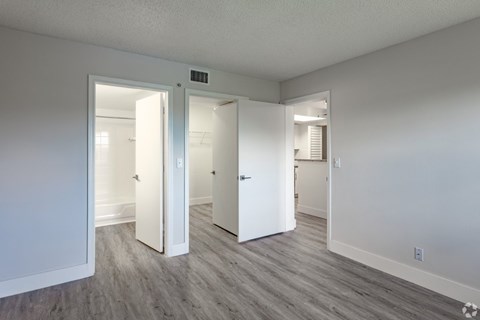 A room with white walls and a grey floor with a doorway leading to another room.
