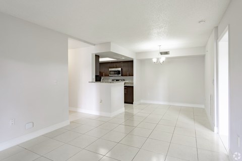 A white tiled kitchen and living room with a bar area.