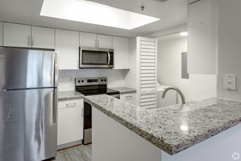 A kitchen with a granite countertop and stainless steel appliances.