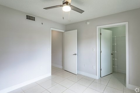 A white room with a ceiling fan and three doors.