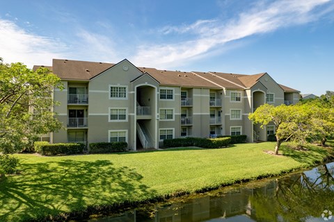 A large apartment complex with a pond in front.