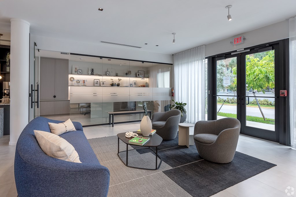A modern living room with a blue sofa and a glass wall.