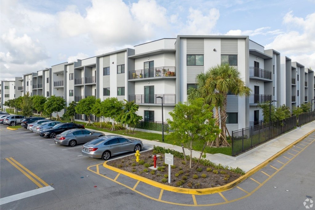 A parking lot with cars and apartment buildings in the background.
