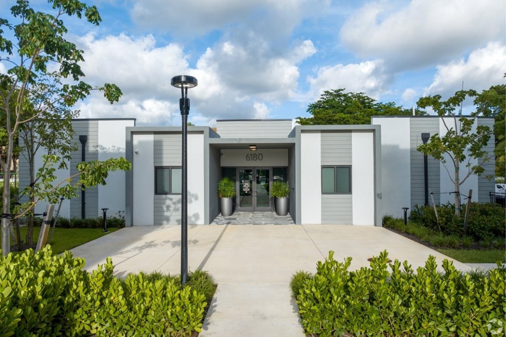 The image shows a modern building with a glass entrance and a sign that reads "B160".