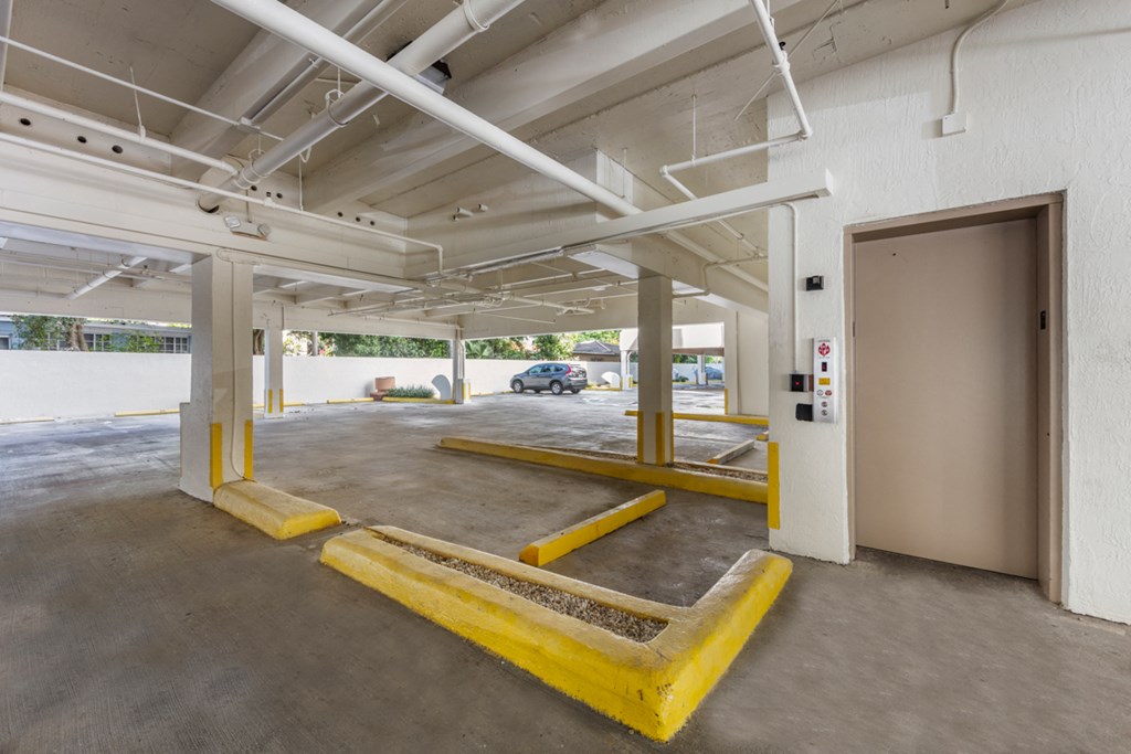 the parking garage of a building with yellow parking meters and a door