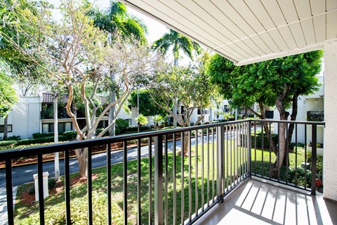 A balcony with a metal railing and trees in the background.