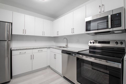 A modern kitchen with white cabinets and stainless steel appliances.