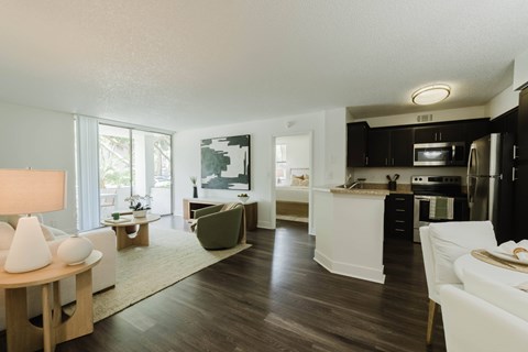 A modern kitchen with dark wood floors and white appliances.