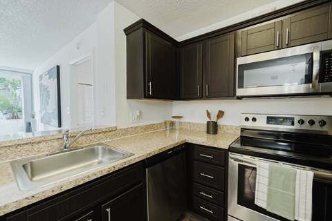 A kitchen with black cabinets and a stainless steel oven.