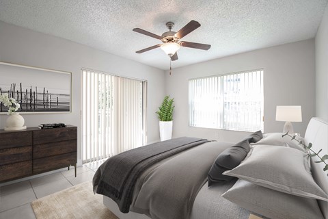 A bedroom with a bed, dresser, and ceiling fan.