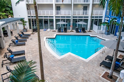 A large swimming pool surrounded by lounge chairs and umbrellas.
