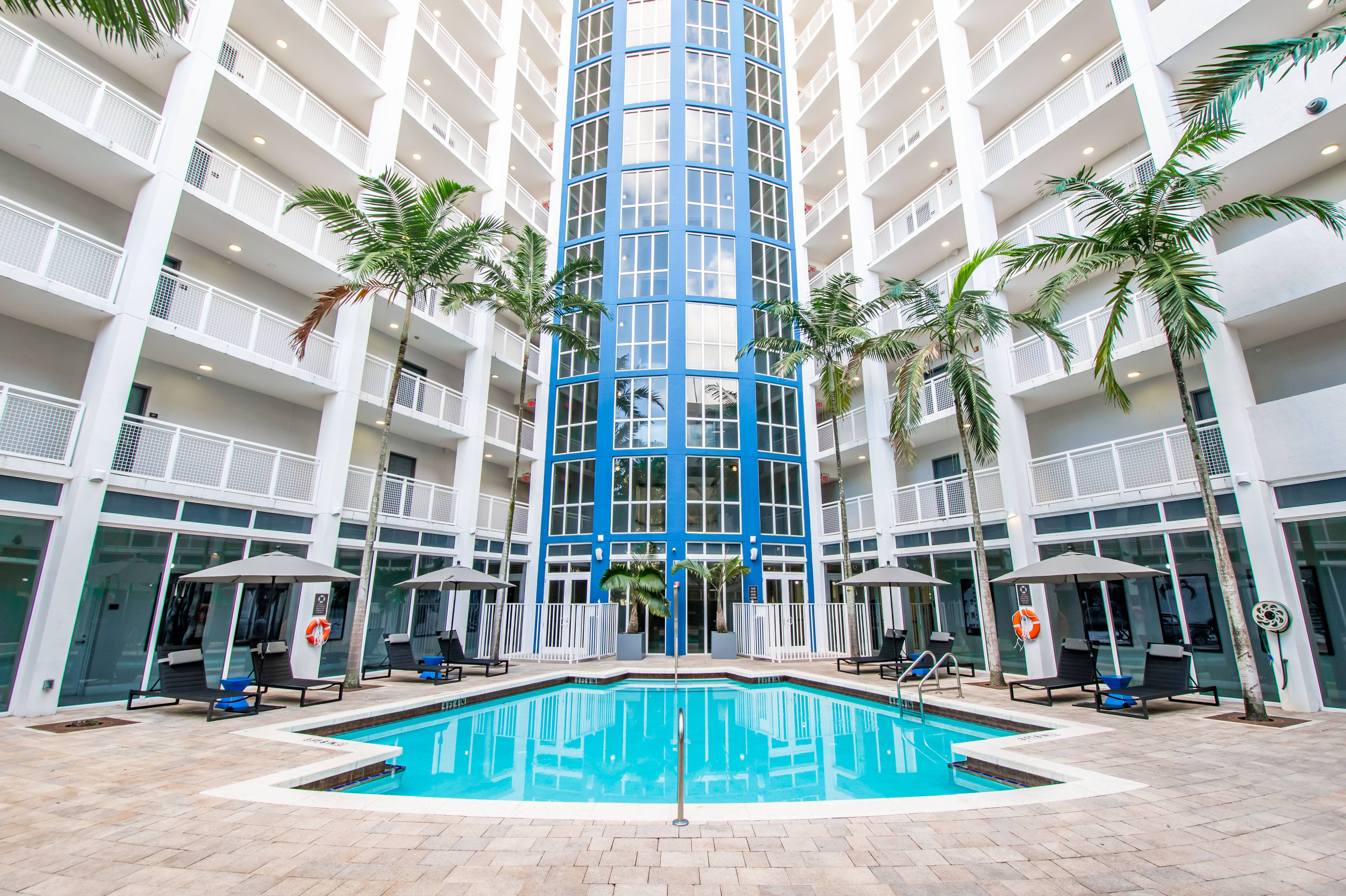 A large indoor swimming pool in a building surrounded by palm trees.