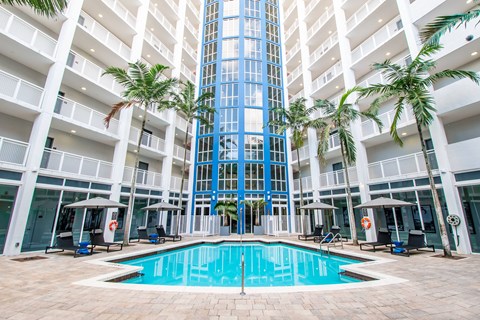 A large indoor swimming pool in a building surrounded by palm trees.
