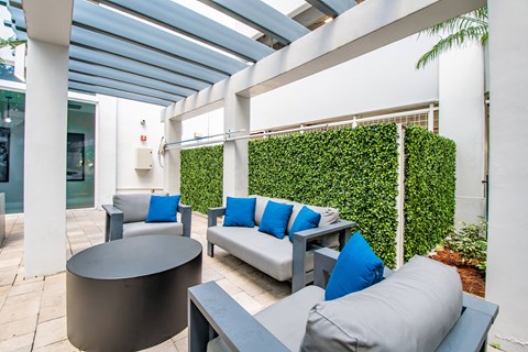 A patio with a white couch and blue pillows.