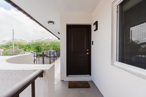 A brown door is on the right side of a white wall.