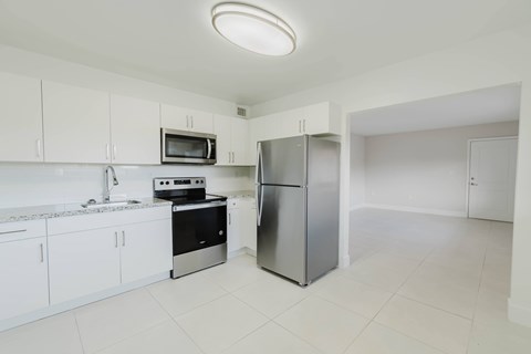 A kitchen with white cabinets and a stainless steel refrigerator.