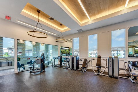a gym with cardio machines and windows with a view of the city