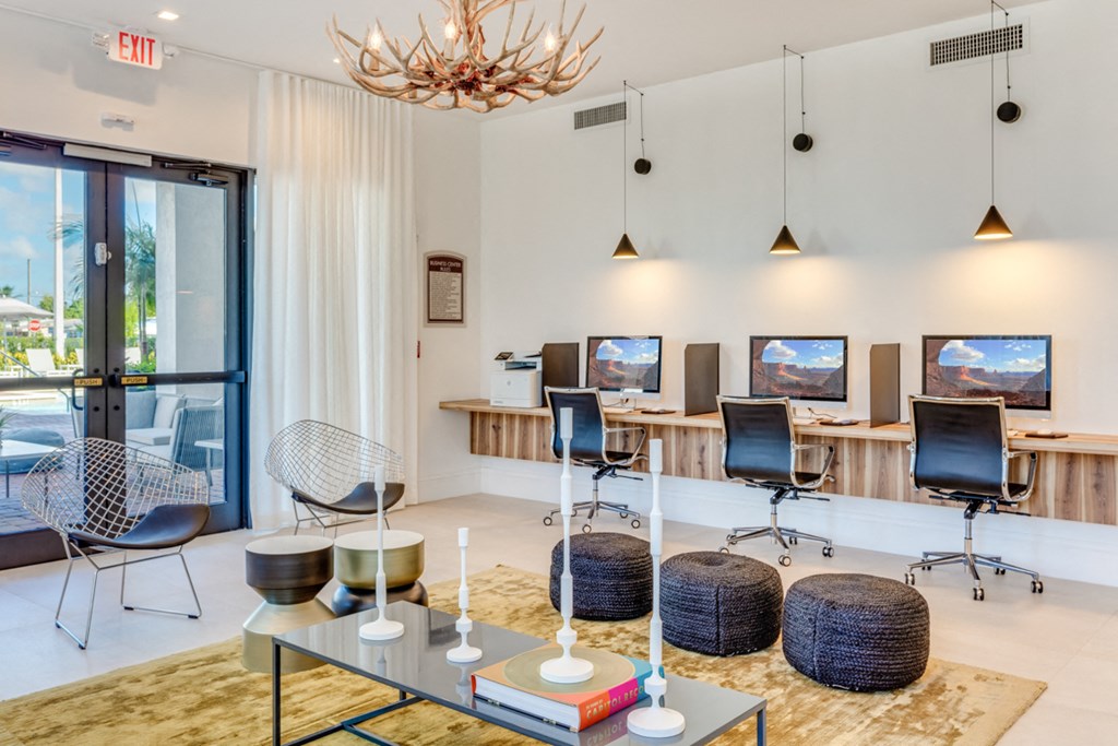 a lounge area with chairs and tables and televisions and a chandelier